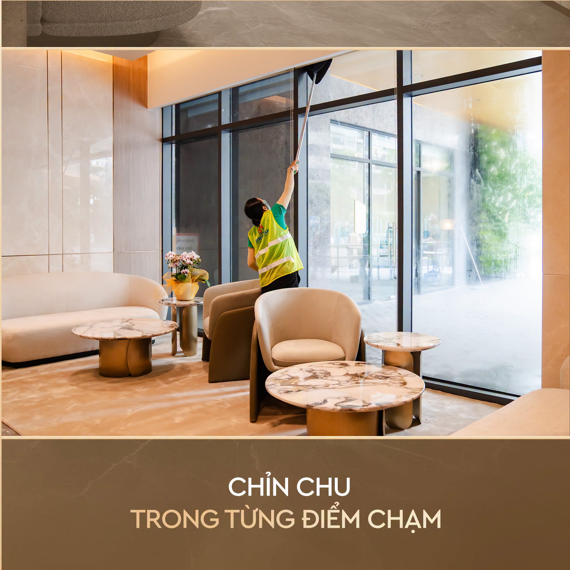 Một nhân viên vệ sinh đang lau cửa kính lớn trong khu vực sảnh/phòng chờ sang trọng.